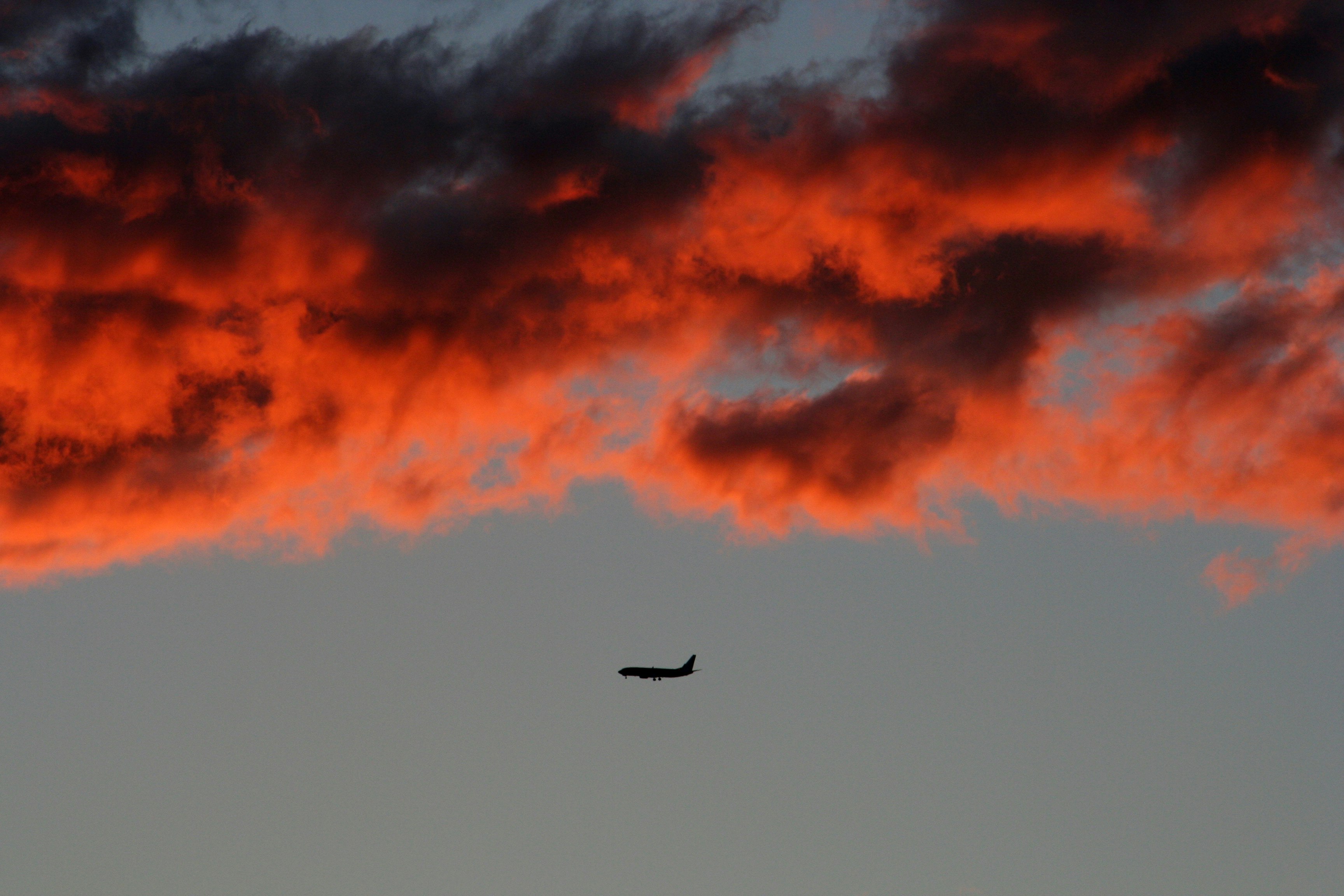 silhouette of plane on air under orange sky